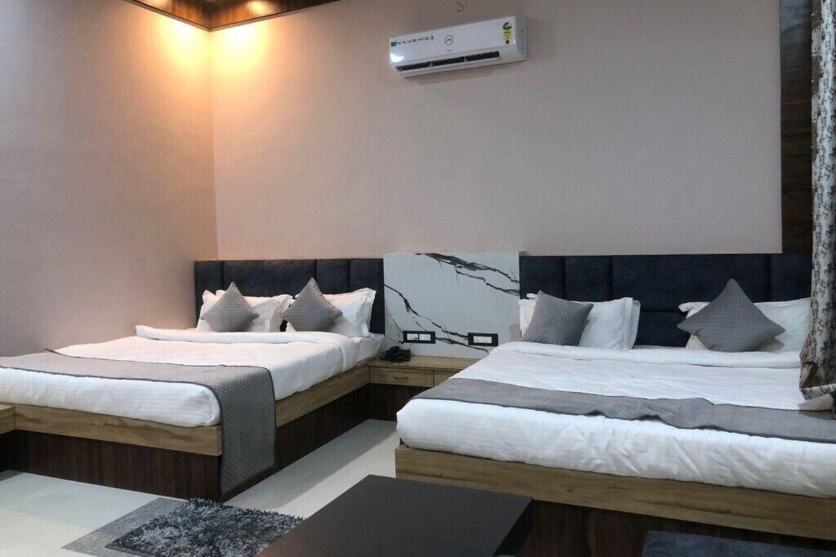 A modern hotel room with two beds, a flat-screen TV, and an air conditioning unit.