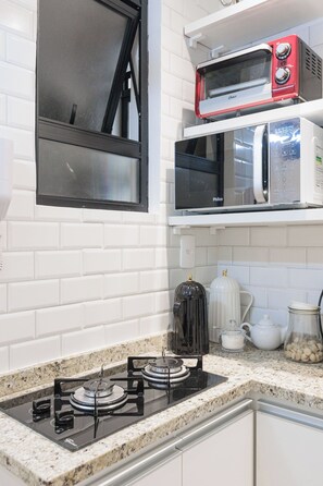A kitchen with a gas stove, a microwave, and a toaster oven on the countertop. - Copacabana Beach Apartment (Rio de Janeiro)