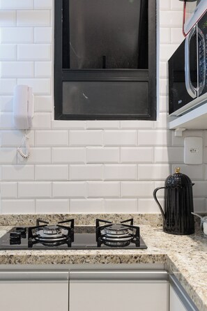 Una cocina con estufa a gas, cafetera y microondas.