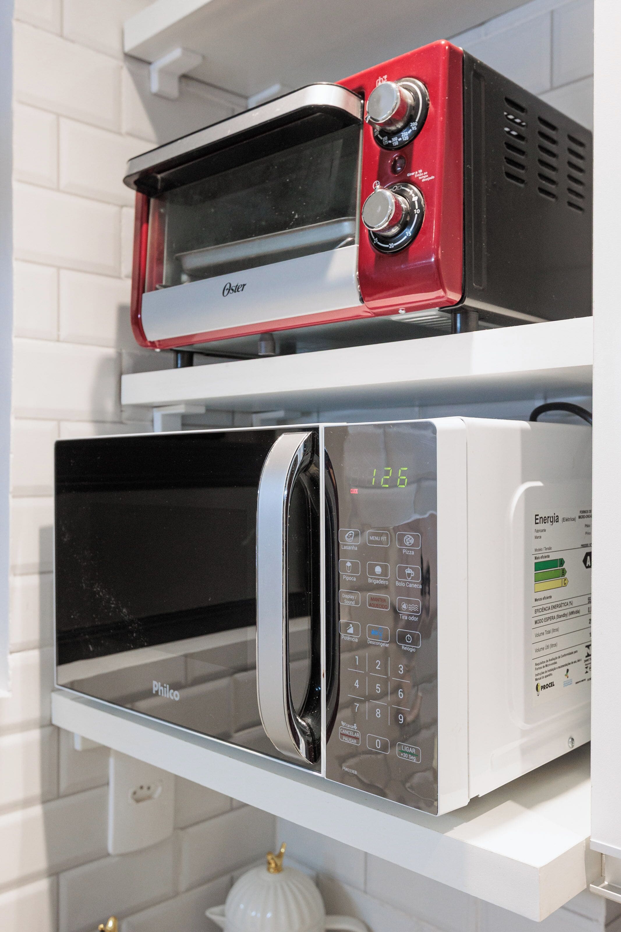Una cucina con un piano di lavoro bianco e due forni, uno rosso e uno bianco, dotati di display digitali.