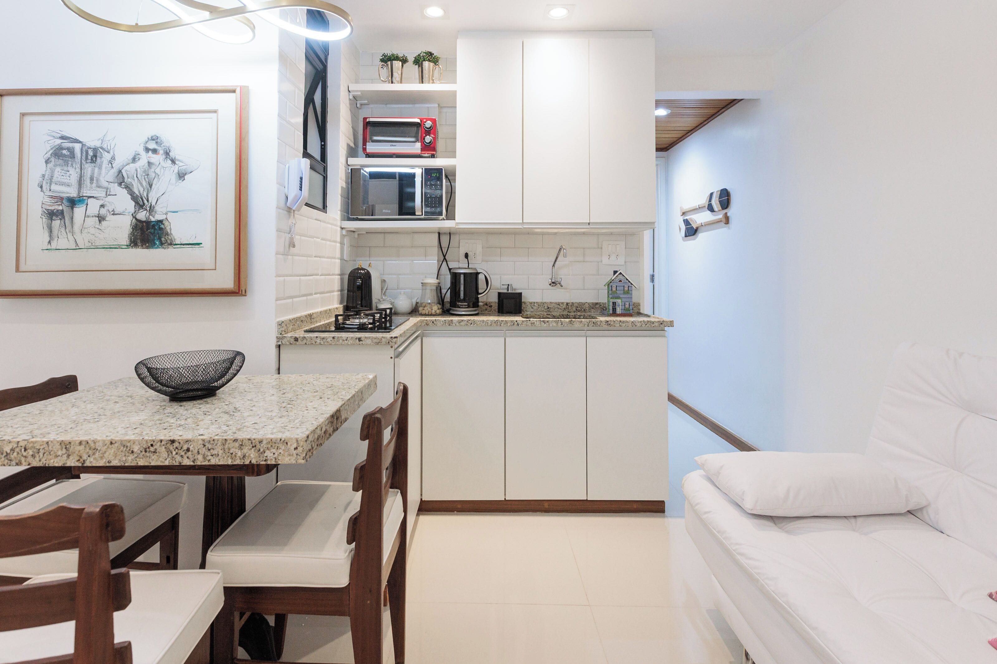 Una cocina funcional con comedor, un sofá blanco y un cuadro enmarcado en la pared.