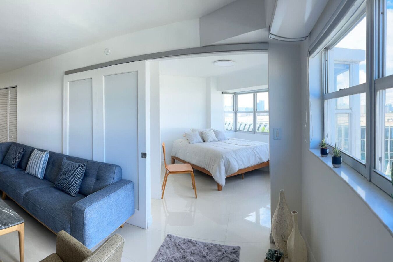 A modern bedroom with a bed, a sofa, and a window with a view.