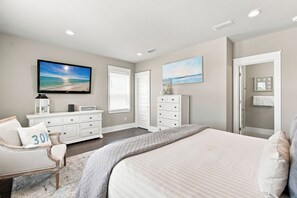 Un dormitorio con cama, cómoda y televisor en la pared.