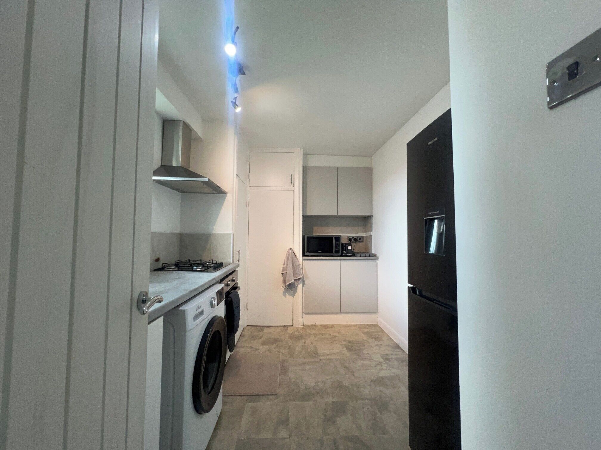 A compact kitchen with a washing machine, a stove, a microwave, and a refrigerator.