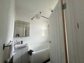 A bathroom with a white sink, mirror, and bathtub. - Wimbledon 2br Free Parking Fast Wi-fi Near Tube (London)