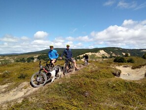Un groupe de personnes sur un sentier de VTT, avec un ciel dégagé et un paysage vallonné en arrière-plan.