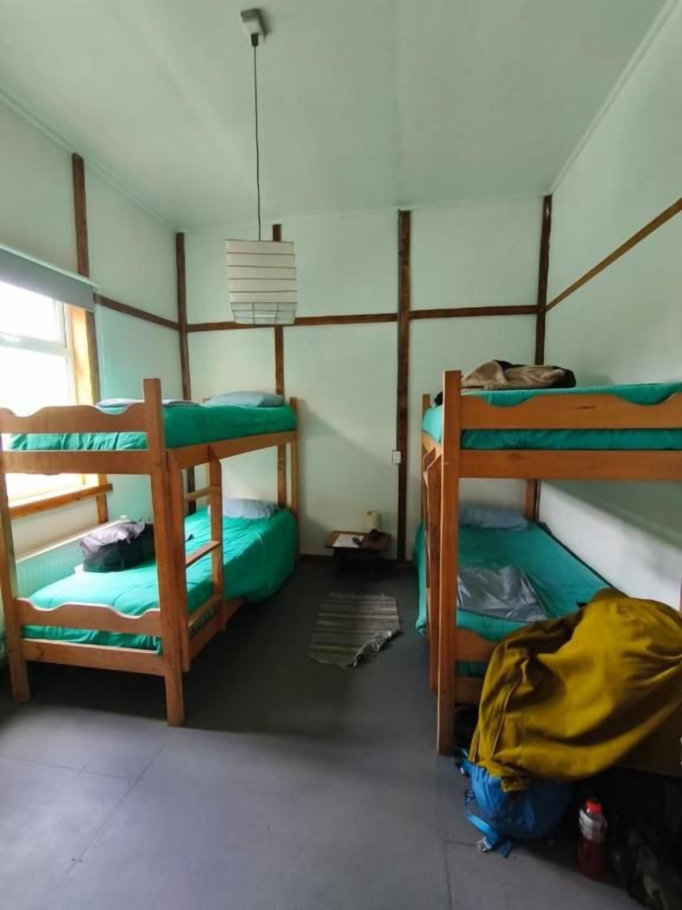 Une chambre de dortoir avec des lits superposés, un luminaire suspendu et une fenêtre.