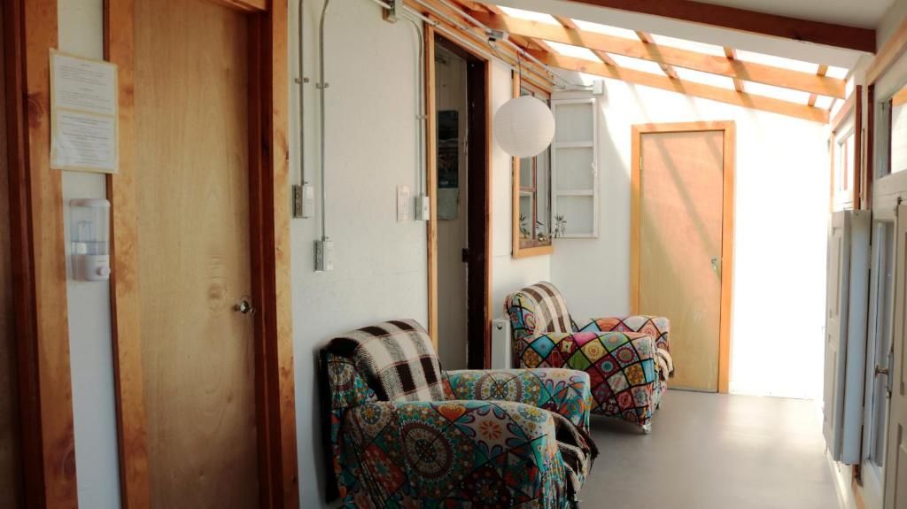 Un couloir avec deux fauteuils à motifs, une porte en bois et une fenêtre donnant sur un paysage.