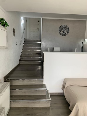 A staircase leading to a landing with a wall-mounted decorative piece. - Charming apartment with views of the sea and mountains (Roses)