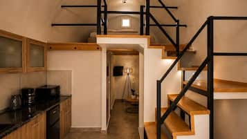 A modern kitchen with a wooden countertop, a coffee machine, and a black refrigerator.