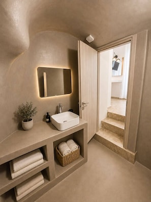 Un baño moderno con lavamanos integrado, un espejo, una planta en maceta y un perchero para toallas.