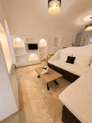 A modern living room with a white sofa, a coffee table, and a TV mounted on the wall.