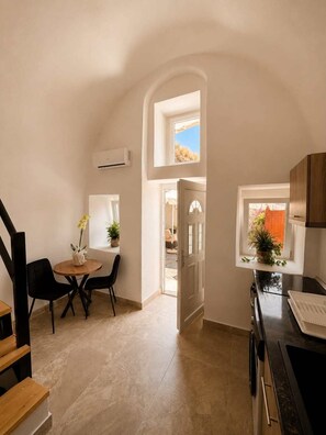 Cocina compacta con comedor, una escalera y vistas a través de un ventanal abierto.