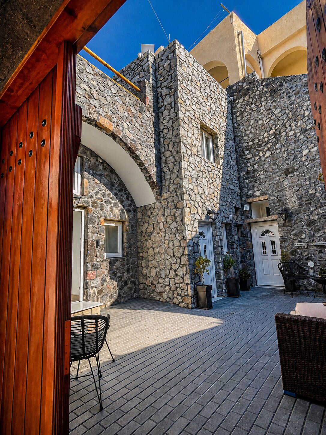 A courtyard with stone walls, a wooden door, and outdoor seating.