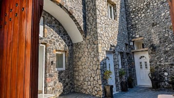 A courtyard with stone walls, a wooden door, and outdoor seating.