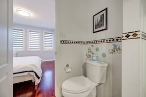 Et soveværelse med seng og badeværelse med toilet og bruser.