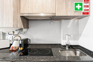 A modern kitchen with a built-in stove, a sink, and wooden cabinets. - GuestReady - City centre stay in Porto (Porto)