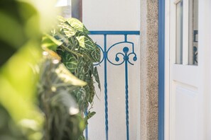 A white door with a blue metal gate and a plant in the foreground. - GuestReady - City centre stay in Porto (Porto)
