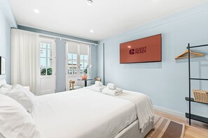 A modern hotel room with a bed, a small table with a vase, a hanging coat rack, and a 'GUEST READY' sign on the wall. - GuestReady - City centre stay in Porto (Porto)