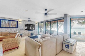 Een moderne woonkamer met een grote bank, een televisie en uitzicht op het strand.