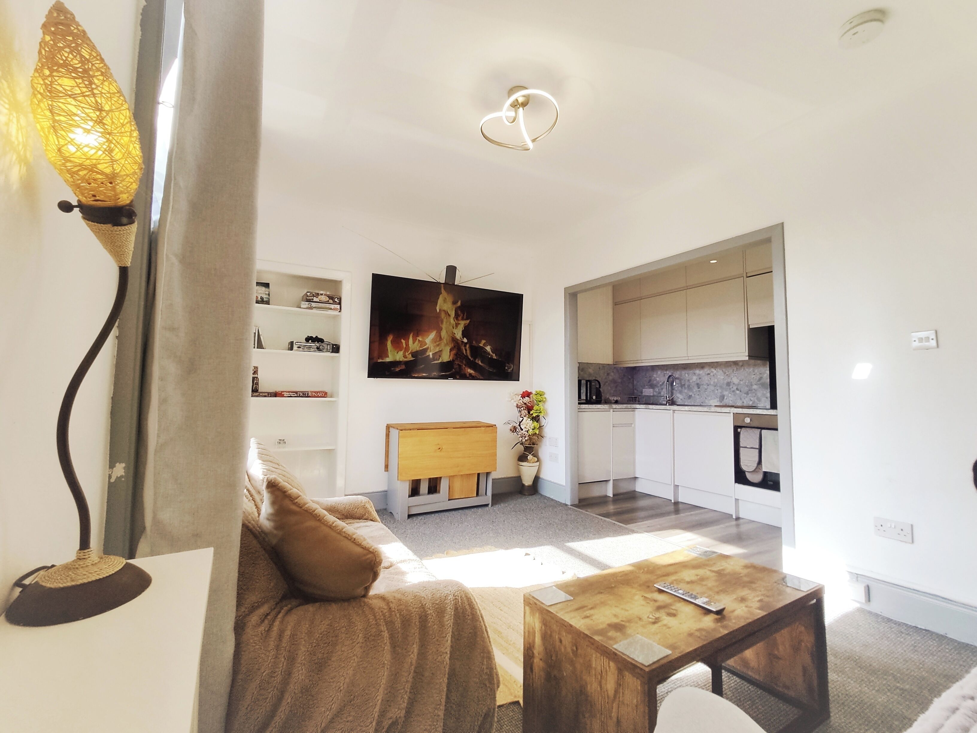 Een moderne woonkamer met een bank, een salontafel en een aan de muur bevestigde televisie.