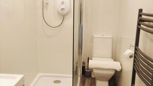 Um banheiro moderno com chuveiro em gabinete de vidro, vaso sanitário e banheira.