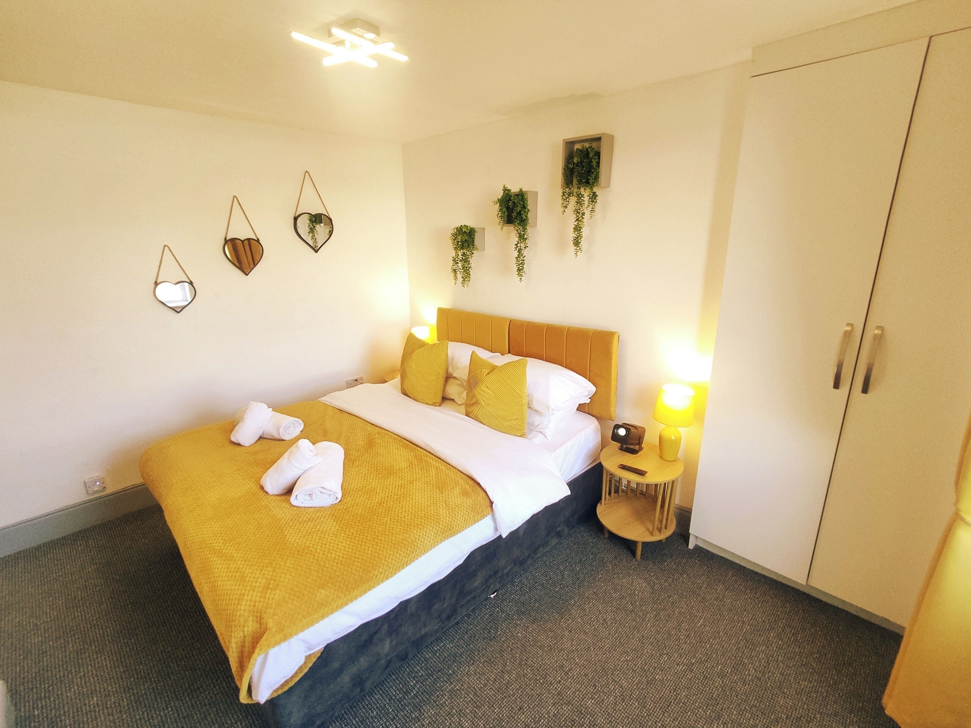 A hotel room with a bed, bedside lamps, a wardrobe, and wall decorations.