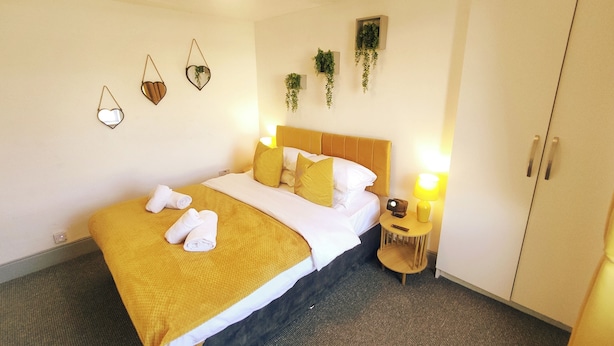 Quarto de hotel com cama, abajures, guarda-roupa e decorações nas paredes.