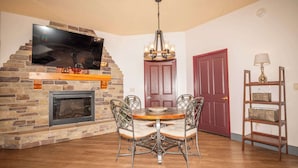 A dining area with a brick fireplace, a flat-screen TV, a chandelier, and a red door. - Chula Condo 2237 & 2239 (Wisconsin Dells)