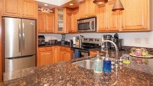 A kitchen with wooden cabinets, stainless steel appliances, granite countertops, and pendant lighting. - Chula Condo 2237 & 2239 (Wisconsin Dells)