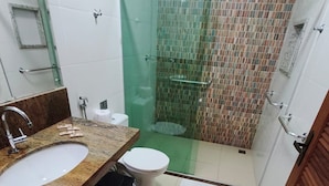 A bathroom with a marble sink, toilet, and a glass-enclosed shower area. - Pousada Praia Grande (Fundão)