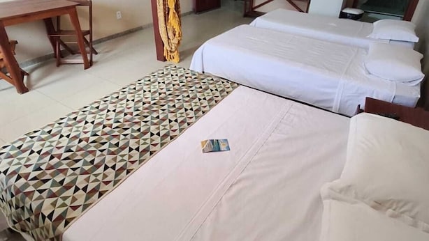 A hotel room with two beds, a desk, and a refrigerator. - Pousada Praia Grande (Fundão)