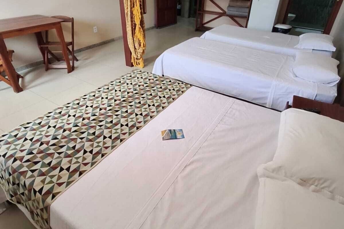 A hotel room with two beds, a desk, and a refrigerator.