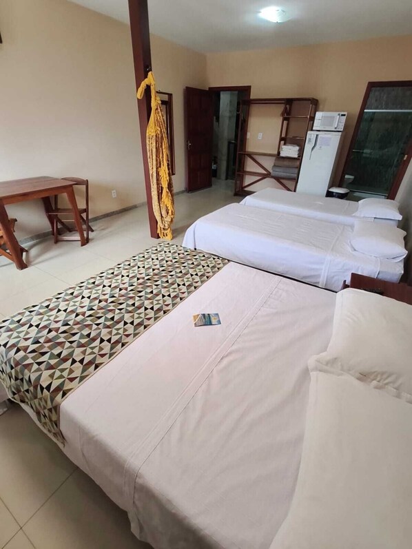 A hotel room with two beds, a desk, and a refrigerator. - Pousada Praia Grande (Fundão)