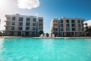 A modern hotel with a swimming pool and multiple balconies. - NOK Stylish 2BR Retreat at Residences Vistacana (Punta Cana)