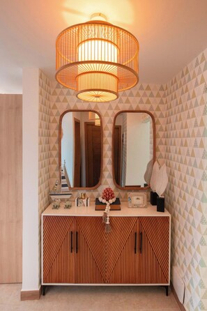 A bathroom with a wooden vanity, two mirrors, and a hanging light fixture. - NOK Stylish 2BR Retreat at Residences Vistacana (Punta Cana)