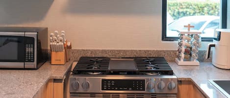 Une cuisine moderne équipée d’une cuisinière intégrée, d’un four à micro-ondes et d’une grande fenêtre.