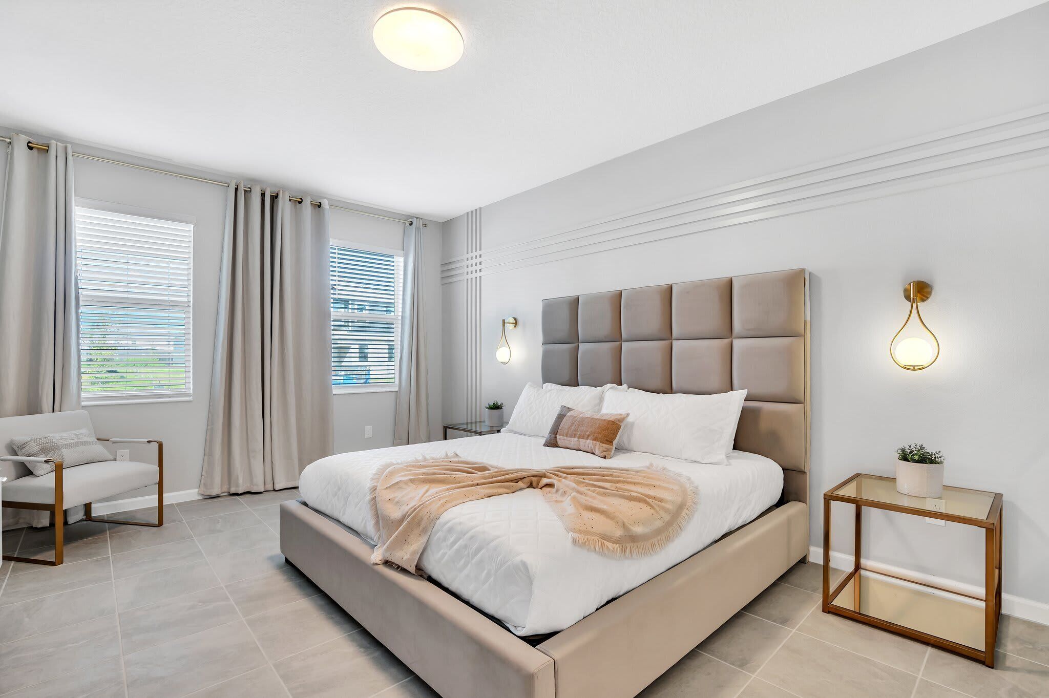 A modern bedroom with a large bed, a bedside table, a chair, and a window with curtains.