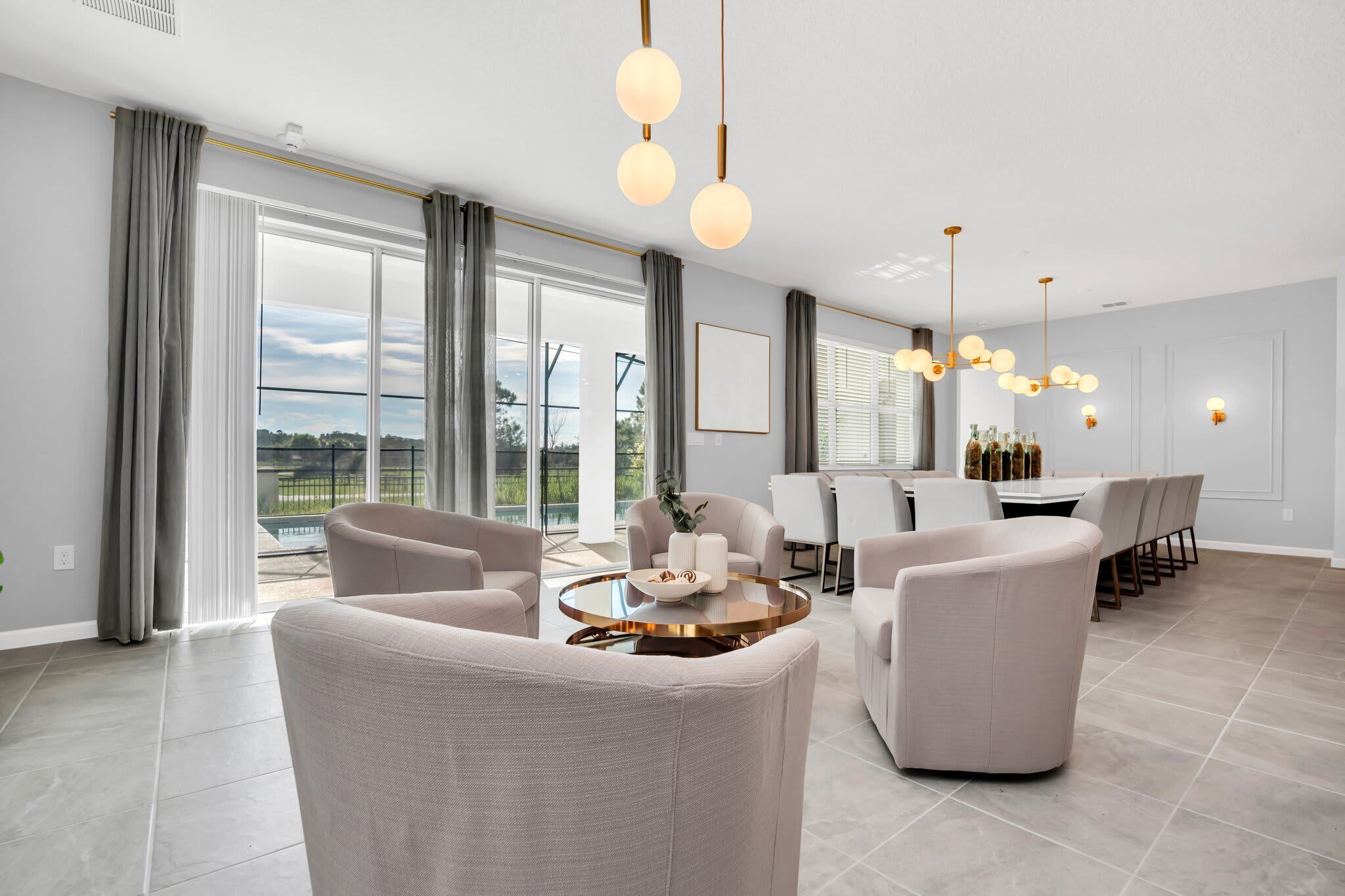 Een ruime woonkamer met een groot raam, een ronde salontafel en een eettafel met stoelen.