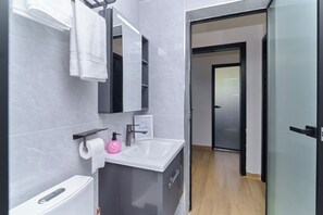 A modern bathroom with a white sink, a mirror, a towel rack, and a toilet. - 2-bedroom apartment with three beds in charming westlands-Nairobi (Nairobi)