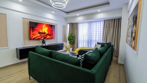 Ein modernes Wohnzimmer mit Flachbildfernseher, grünem Sofa und einer Pflanze.