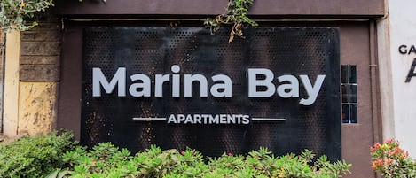 Une enseigne pour les « appartements Marina Bay », avec un design moderne et de la verdure à l’avant.