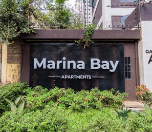 Schild für 'Marina Bay Apartments' mit modernem Design und begrüntem Vorbereich.