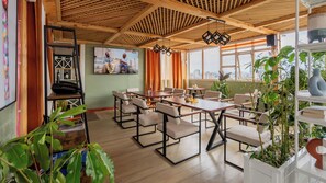 A dining area with wooden tables and chairs, a television mounted on the wall, and large windows with curtains. - 2-bedroom apartment with three beds in charming westlands-Nairobi (Nairobi)