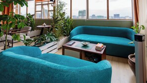 A modern living room with a teal sofa, a wooden coffee table, and a view of the cityscape through large windows. - 2-bedroom apartment with three beds in charming westlands-Nairobi (Nairobi)