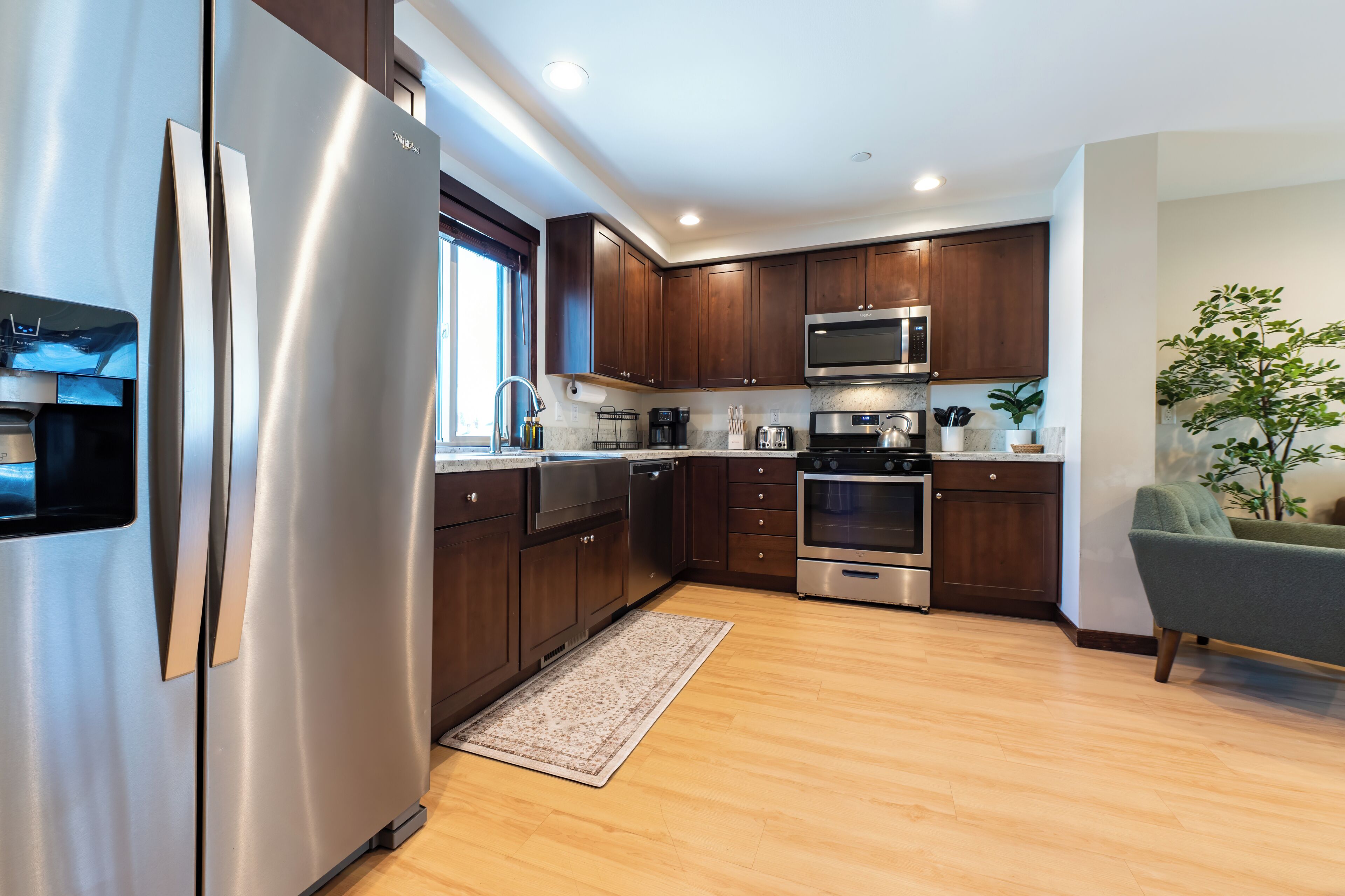 Una cocina moderna con electrodomésticos de acero inoxidable, armarios de madera y un sillón verde.