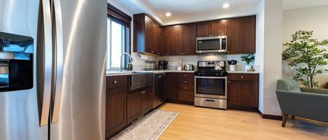 Una cocina moderna con electrodomésticos de acero inoxidable, armarios de madera y un sillón verde.