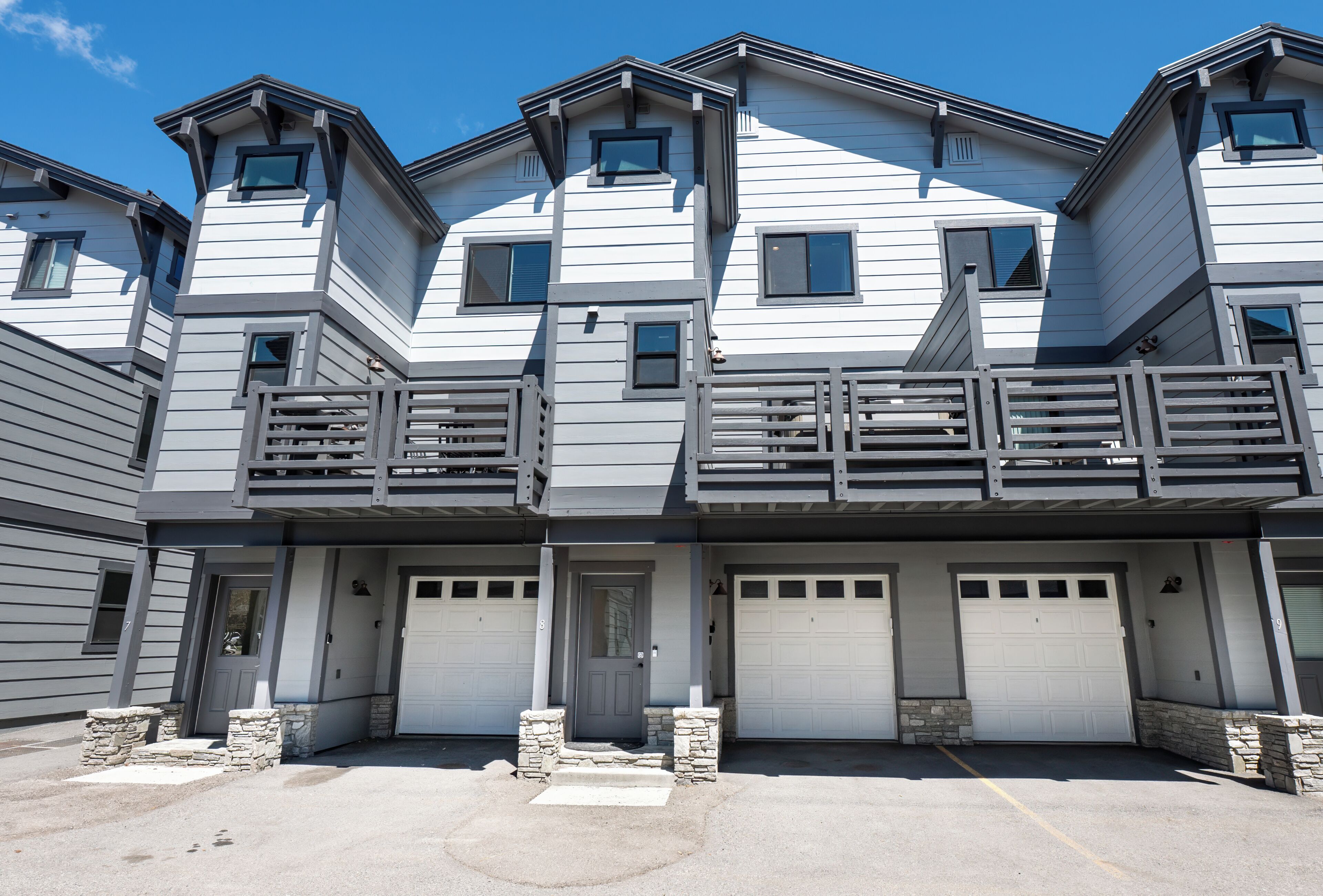 A multi-story residential building with a garage entrance, stone steps, and a balcony.