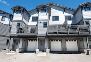 Ein mehrstöckiges Wohngebäude mit einer Garage, Steinstufen und einem Balkon.