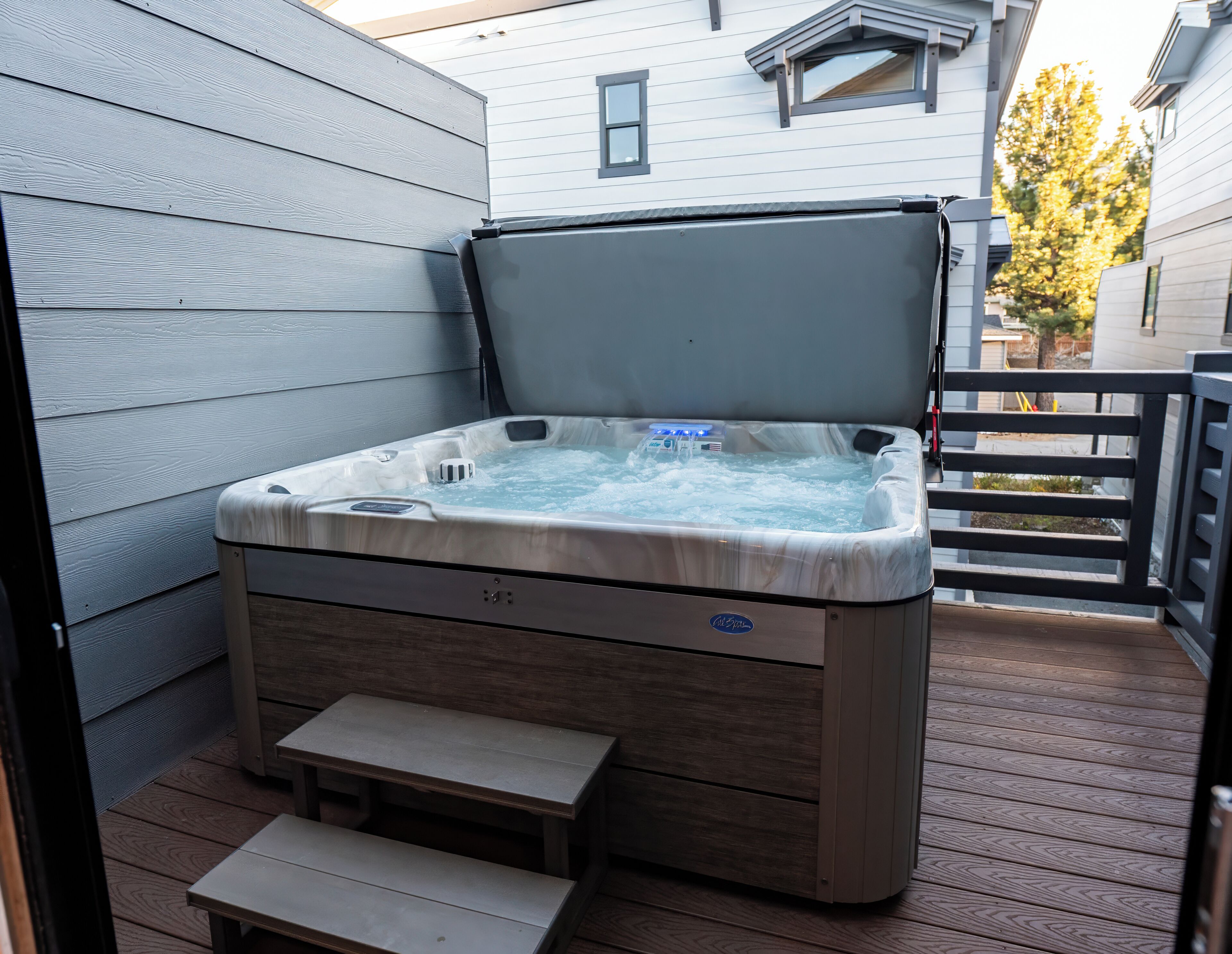 A hot tub on a wooden deck with a bench in front.